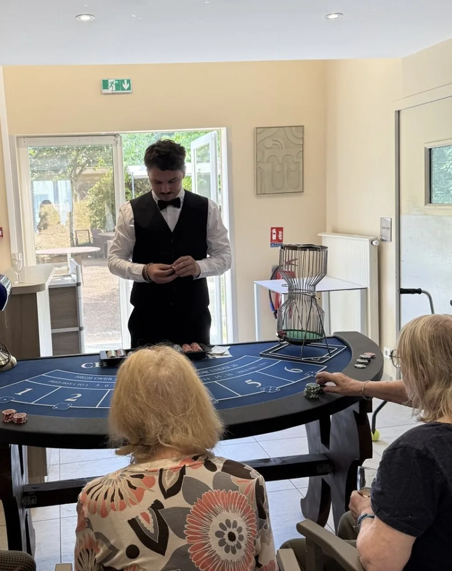 Table de Chuck-a-Luck et sa cage à dés rotative, animée par un croupier face à deux joueuses