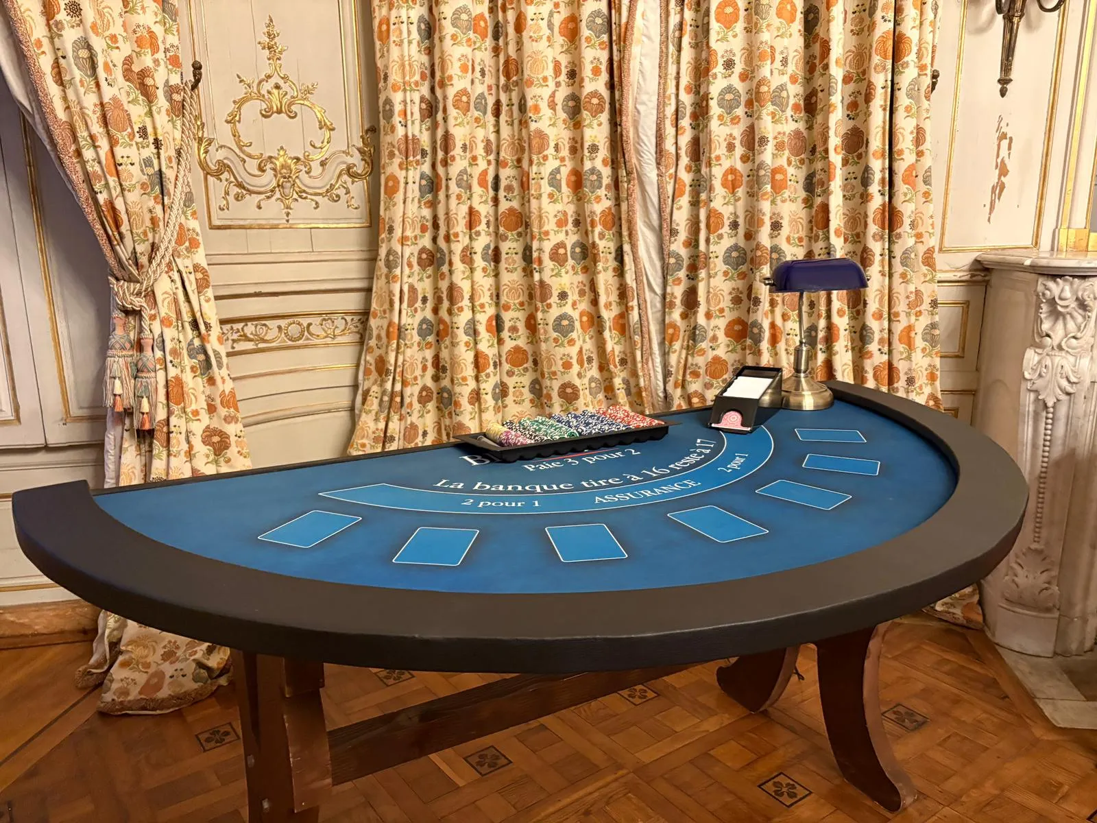 Table de blackjack au tapis bleu installée dans un salon du château