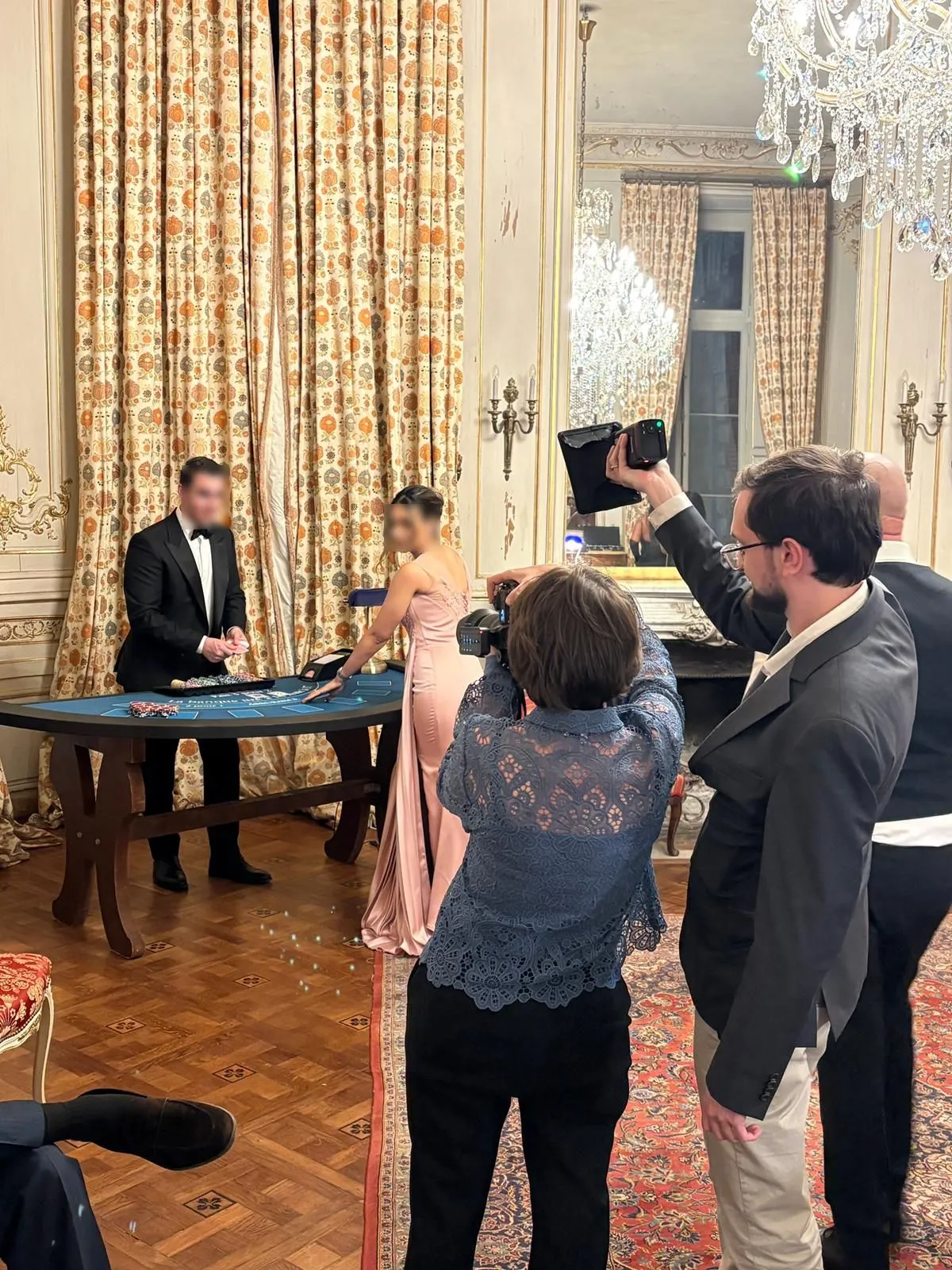 Croupier en smoking animant une table de casino près d'une invitée en robe longue